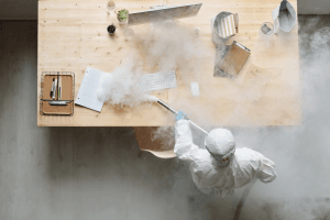 A person in a protective suit fumigating a table